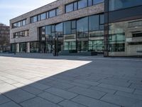 a empty courtyard in front of buildings on a sunny day with some cars on the ground