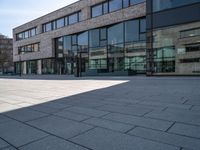 a empty courtyard in front of buildings on a sunny day with some cars on the ground