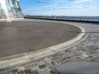 a person riding on top of a skateboard on a paved surface by water's edge