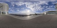 fisheye lens of the sea shore with buildings and a cloudy blue sky in the background