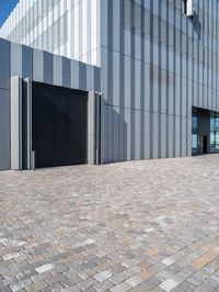 an industrial building that has gray metal siding on it's exterior and has a parking space outside