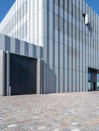 an industrial building that has gray metal siding on it's exterior and has a parking space outside