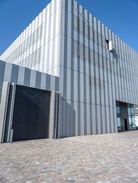 an industrial building that has gray metal siding on it's exterior and has a parking space outside