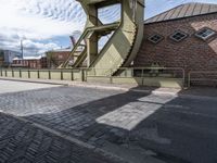 a street with a sidewalk and a bridge leading to it with a clock on the front of it