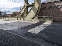 a street with a sidewalk and a bridge leading to it with a clock on the front of it