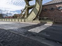 a street with a sidewalk and a bridge leading to it with a clock on the front of it