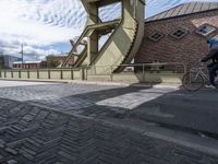 a street with a sidewalk and a bridge leading to it with a clock on the front of it