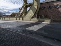 a street with a sidewalk and a bridge leading to it with a clock on the front of it