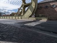 a street with a sidewalk and a bridge leading to it with a clock on the front of it