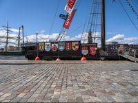 a boat docked on a brick walkway with a flag and flag poles in the background