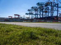 a road running through the grass near a construction crane in an industrial area with green grass