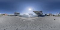 boats sit next to each other on the water in a harbor at night time from a 360 camera