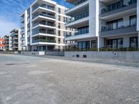 an empty parking lot in front of high rise apartments or apartment complexes, with no sidewalks or trees on the ground