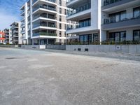 an empty parking lot in front of high rise apartments or apartment complexes, with no sidewalks or trees on the ground