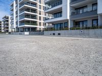 an empty parking lot in front of high rise apartments or apartment complexes, with no sidewalks or trees on the ground