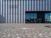 brick path and building with modern glass front door area, which is reflected by glass doors