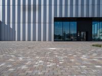 brick path and building with modern glass front door area, which is reflected by glass doors