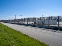 a fenced off entrance to a large industrial facility on a sunny day in the city