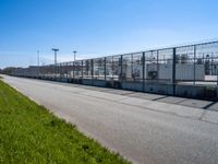 a fenced off entrance to a large industrial facility on a sunny day in the city