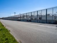 a fenced off entrance to a large industrial facility on a sunny day in the city