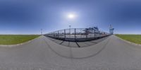 a street scene with a 360 - view lens in action on it and a fence to the left