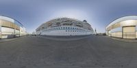 large passenger ship at dock in glass building area of port city, as seen through fisheye lens