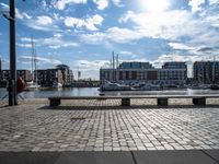 a bench sitting in a city by a body of water, and a bunch of boats on a dock