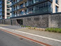 a brick and stone building along the side of the street near cars with people looking out on windows