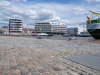 the large boat is docked on the harbor shore of a city near many buildings with windows