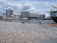 the large boat is docked on the harbor shore of a city near many buildings with windows