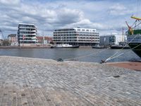 the large boat is docked on the harbor shore of a city near many buildings with windows