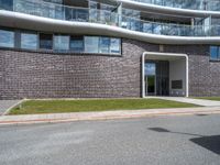 a building with grass next to it on a street corner with cars parked at the curb