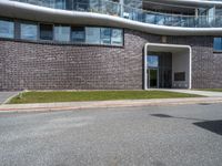 a building with grass next to it on a street corner with cars parked at the curb