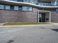 a building with grass next to it on a street corner with cars parked at the curb