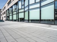 glass - trimmed building with modern parking in front of it on a sidewalk beside a pedestrian