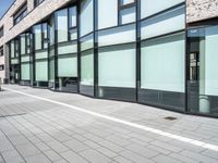 glass - trimmed building with modern parking in front of it on a sidewalk beside a pedestrian