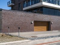 a building is shown with a brick facade and driveway side walk, and an external brown garage door