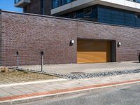 a building is shown with a brick facade and driveway side walk, and an external brown garage door