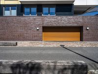 a building is shown with a brick facade and driveway side walk, and an external brown garage door