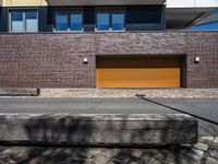 a building is shown with a brick facade and driveway side walk, and an external brown garage door