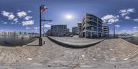 a fish - eye lens of an apartment complex by the water with sailboats in the background