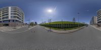 a fish eye view of a city intersection and sidewalk with buildings and trees and the sun shining on it