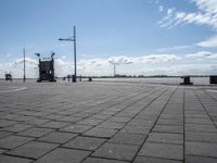 a square stone pavement with a car park in the background on an empty runway with buildings in front