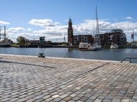 a brick sidewalk is lined up along with boats and buildings in the background on a sunny day