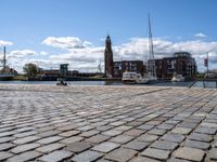 a brick sidewalk is lined up along with boats and buildings in the background on a sunny day