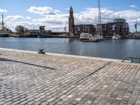 a brick sidewalk is lined up along with boats and buildings in the background on a sunny day