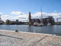 a brick sidewalk is lined up along with boats and buildings in the background on a sunny day