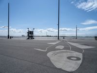 a drawing on asphalt in an airport parking lot with power poles and street lamps in the background