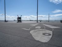 a drawing on asphalt in an airport parking lot with power poles and street lamps in the background