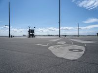 a drawing on asphalt in an airport parking lot with power poles and street lamps in the background